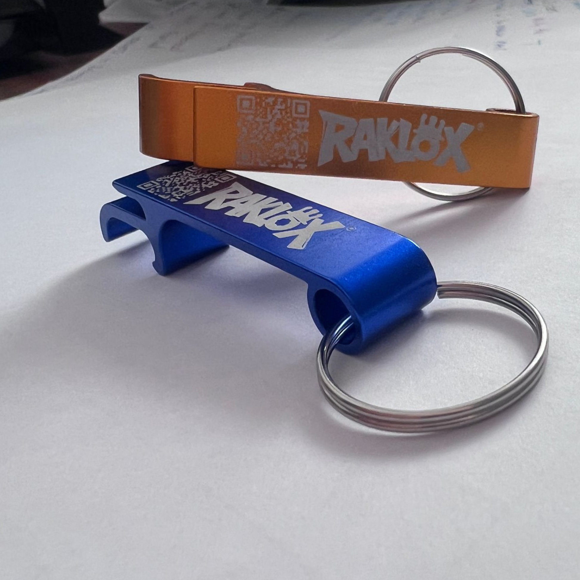 Two bottle openers with 'RAKLOX' branding on a white surface.
