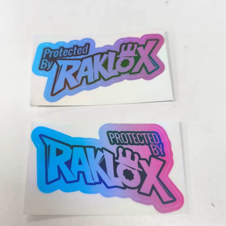 Two die-cut stickers featuring the text 'Protected By RAKLOX' in stylized lettering with a blue-to-pink gradient outline, shown on a plain white background.