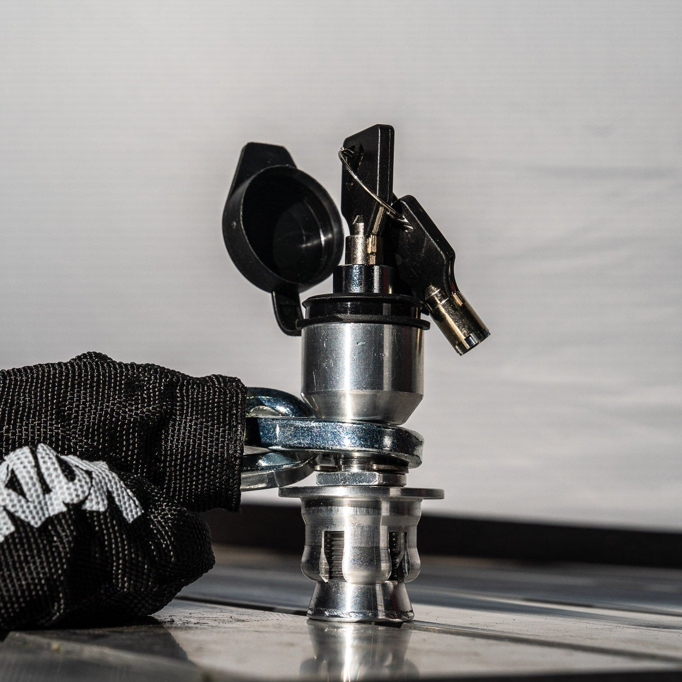 Metallic bike lock with a black chain on a reflective surface