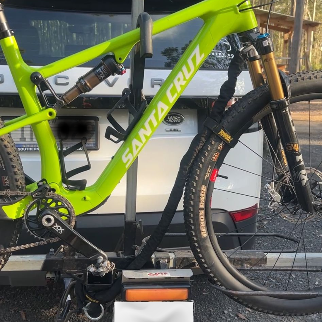 Bright green Santa Cruz mountain bike secured to a rear vehicle bike rack using the Raklox lock system, demonstrating integrated bike rack security during transport.