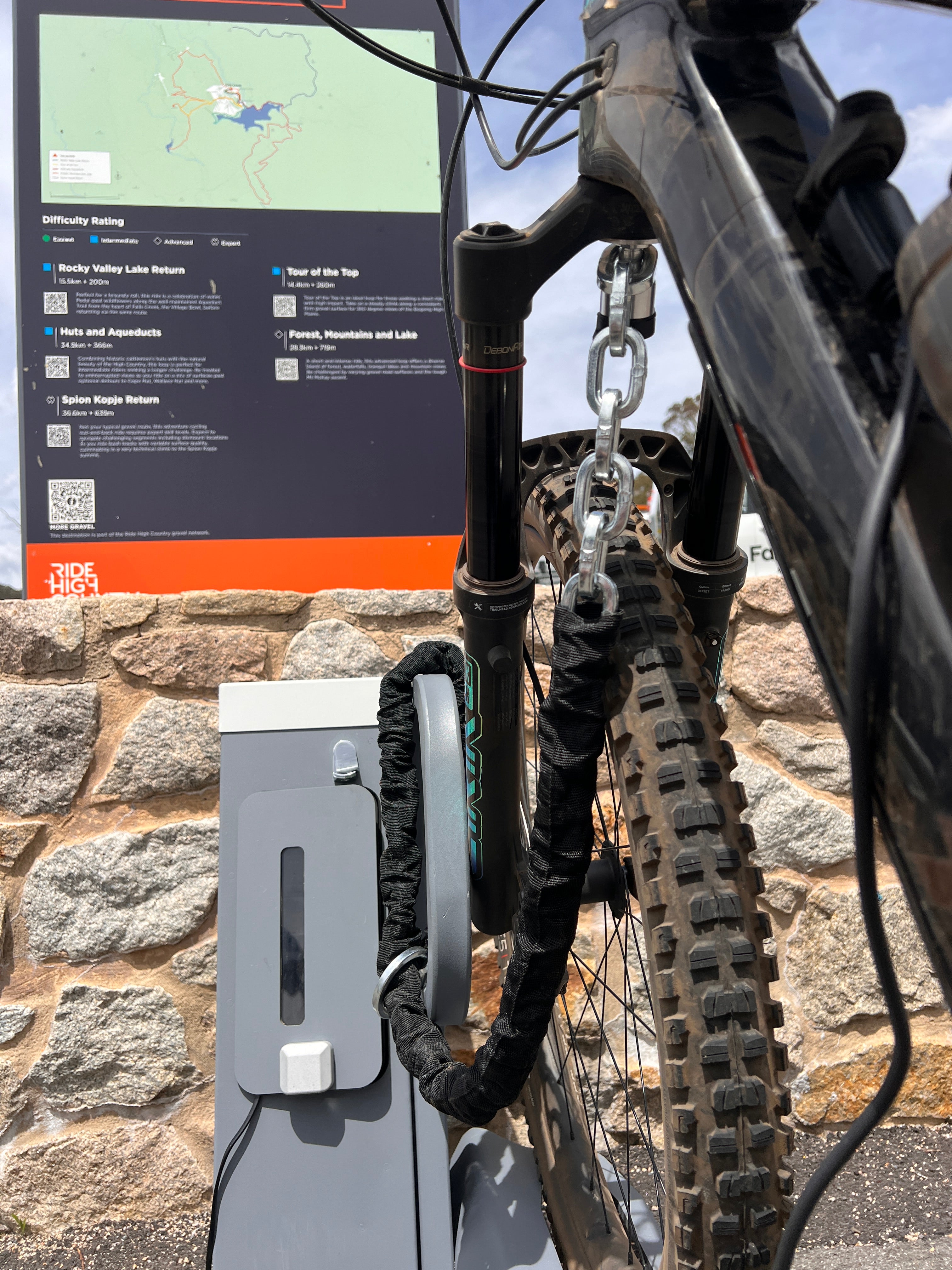 Electric bike connected to charger and protected with travel loop bike rack security lock and padded anti-theft chain.