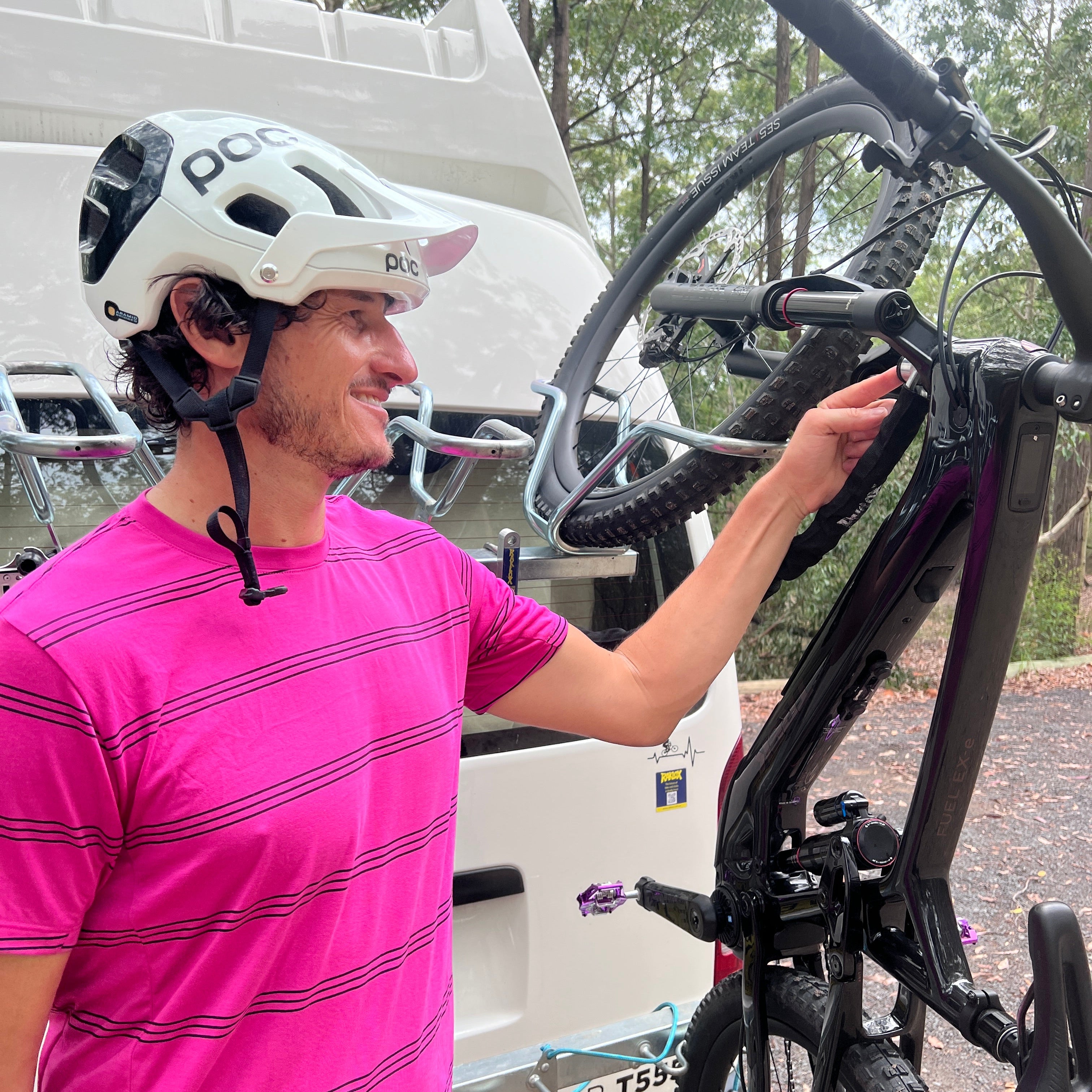 Person in pink shirt and white helmet adjusting a bicycle on a vehicle with raklox.